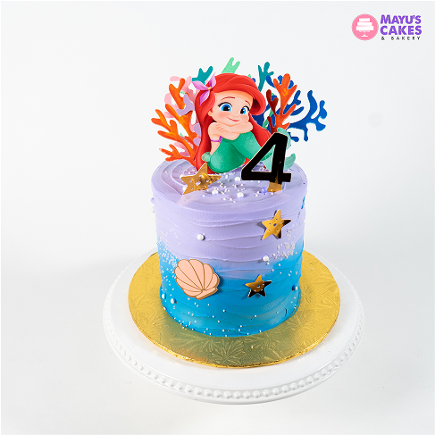Colorful mermaid-themed cake with number four topper and sea decorations.