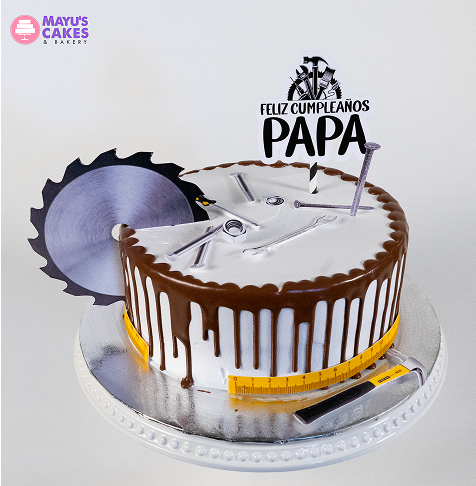 Cake with tools and 'Feliz Cumpleaños Papa' topper, decorated with saw blade and measuring tape.