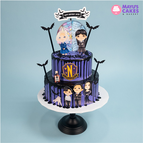 Two-tiered cake with cartoon characters and bat decorations on a blue background.