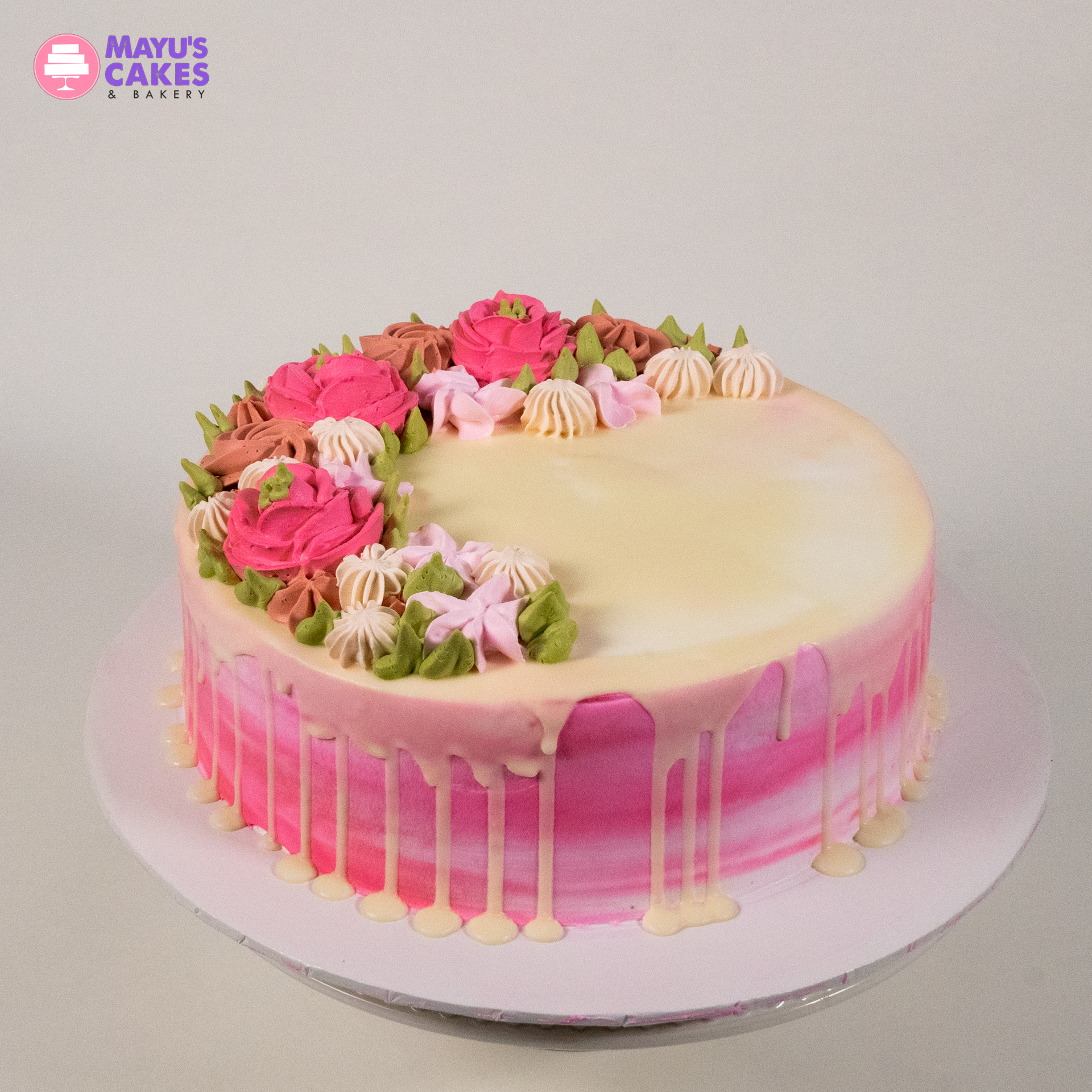 Pink and white cake with floral icing decorations on top.