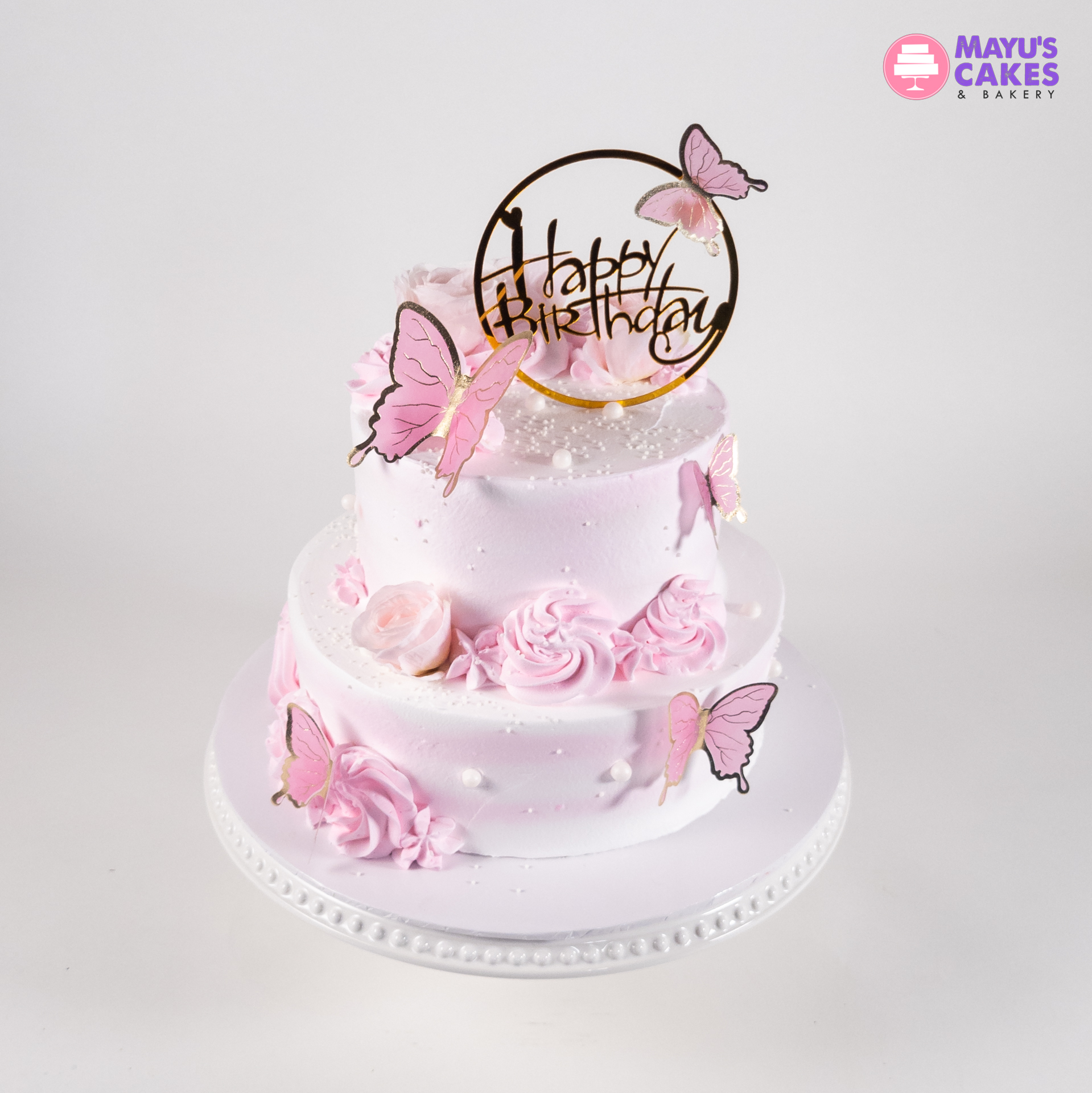 Two-tier pink birthday cake with butterflies and roses.