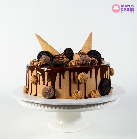 Chocolate cake with cookies, cones, and truffles on a white stand.