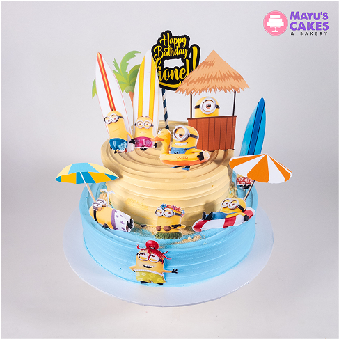 Colorful cake with Minion decorations, surfboards, and a beach theme.