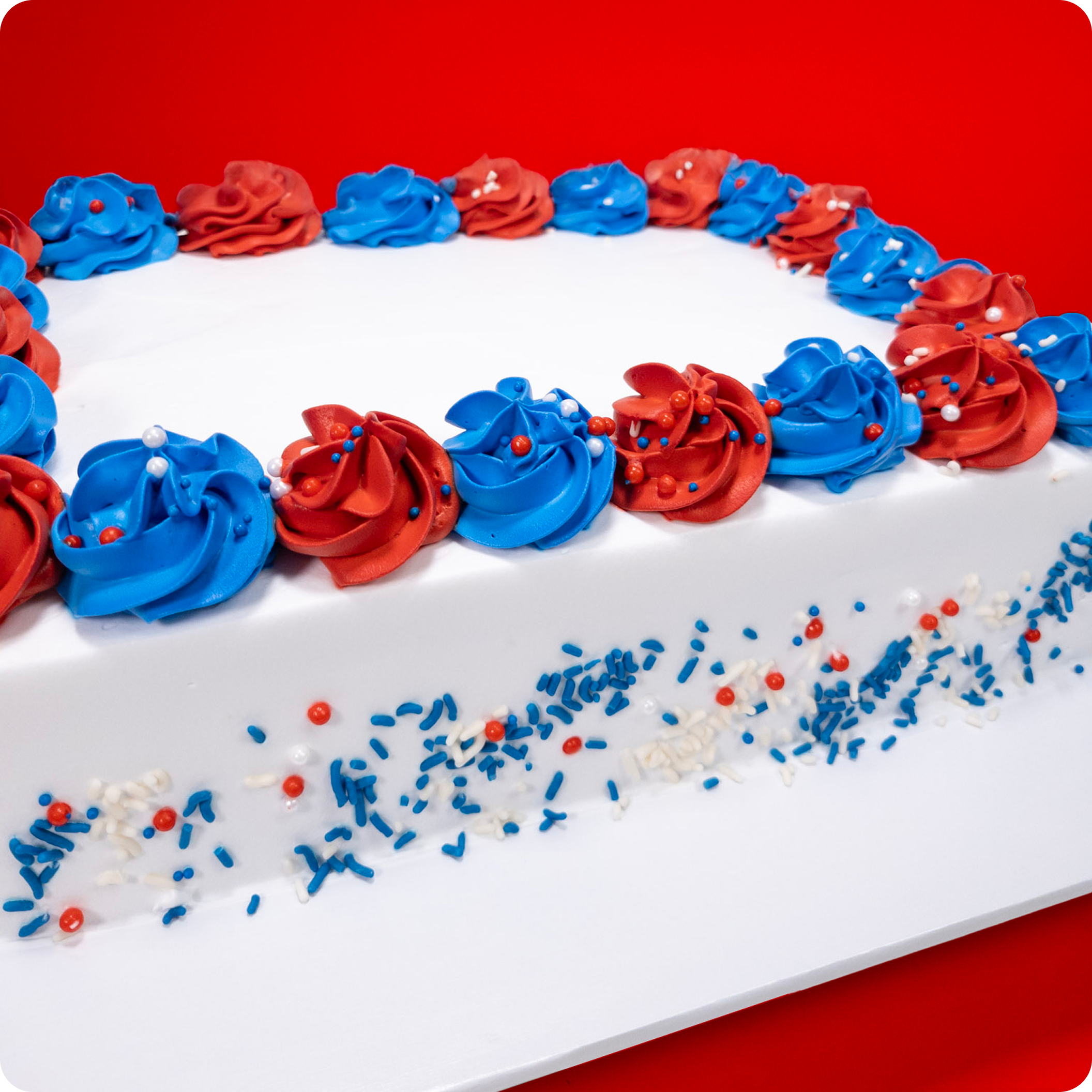 Rectangular cake with red and blue frosting on a red background.
