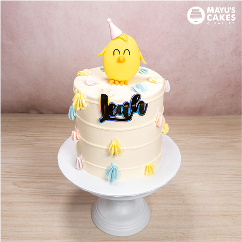 A decorated cake with a yellow chick topper and the name 'Leah' on it.