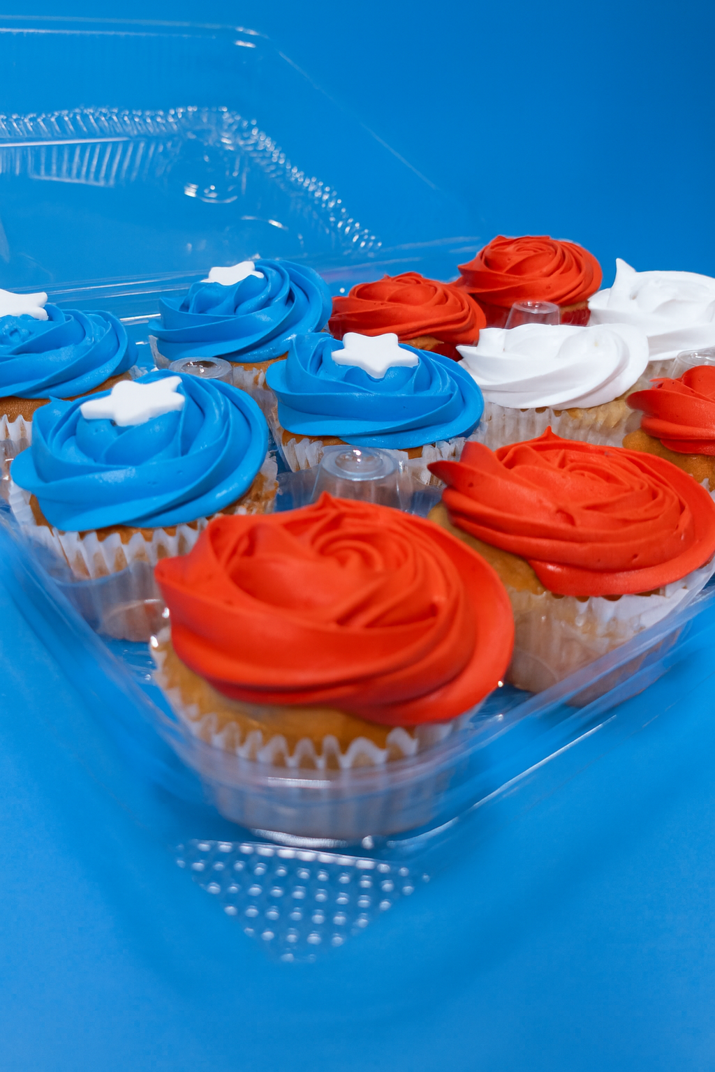 Cupcakes with red, white, and blue frosting in a clear plastic container.