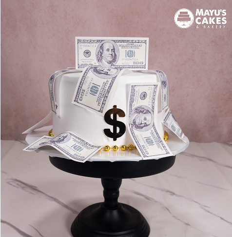 White cake with fake money and dollar sign decoration on a black stand.