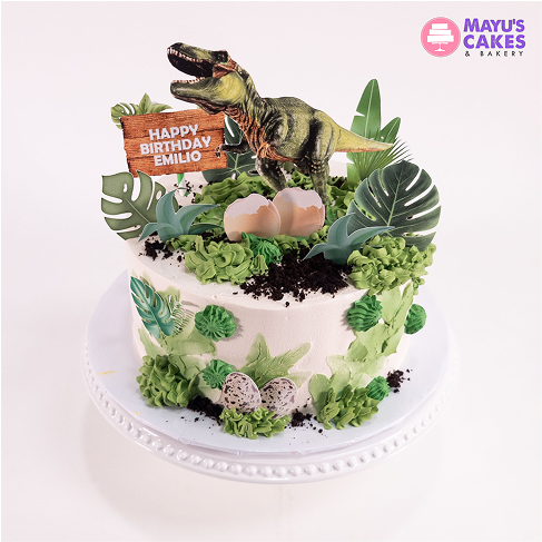 Dinosaur-themed birthday cake with green frosting and a 'Happy Birthday Emilio' sign.