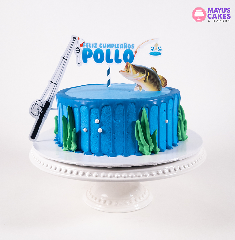 Blue birthday cake with fishing theme decorations on a white stand.