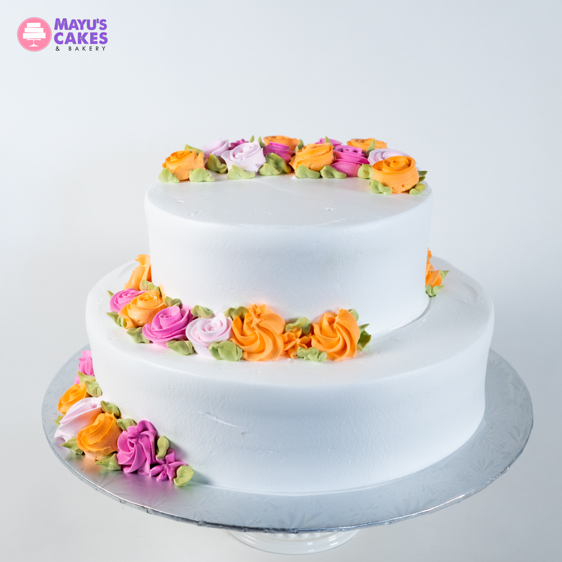 Two-tier white cake with colorful floral decorations.