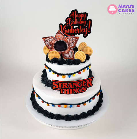 Two-tiered cake with 'Stranger Things' theme, topped with waffles and a Demogorgon flower.