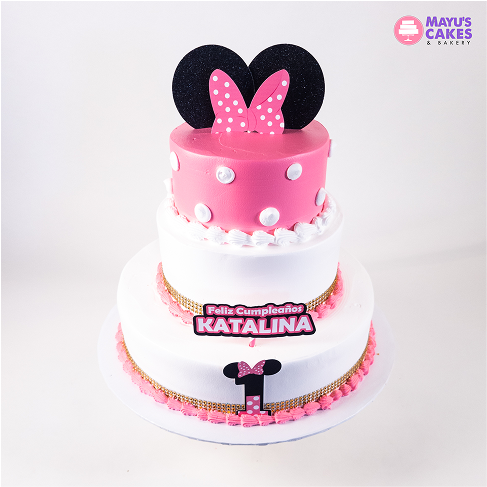 Three-tiered pink and white cake with polka dots and Minnie Mouse ears.