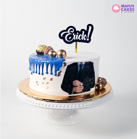 Decorative cake with blue icing, gold accents, and a topper reading 'Erick!' on a white stand.