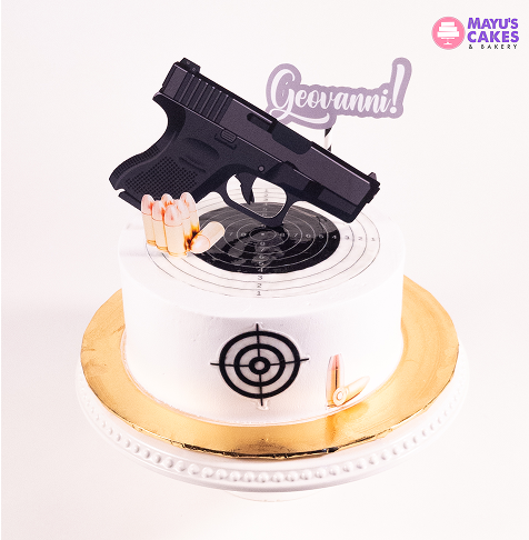 Cake with a gun topper, target design, and bullets, labeled 'Geovanni.'