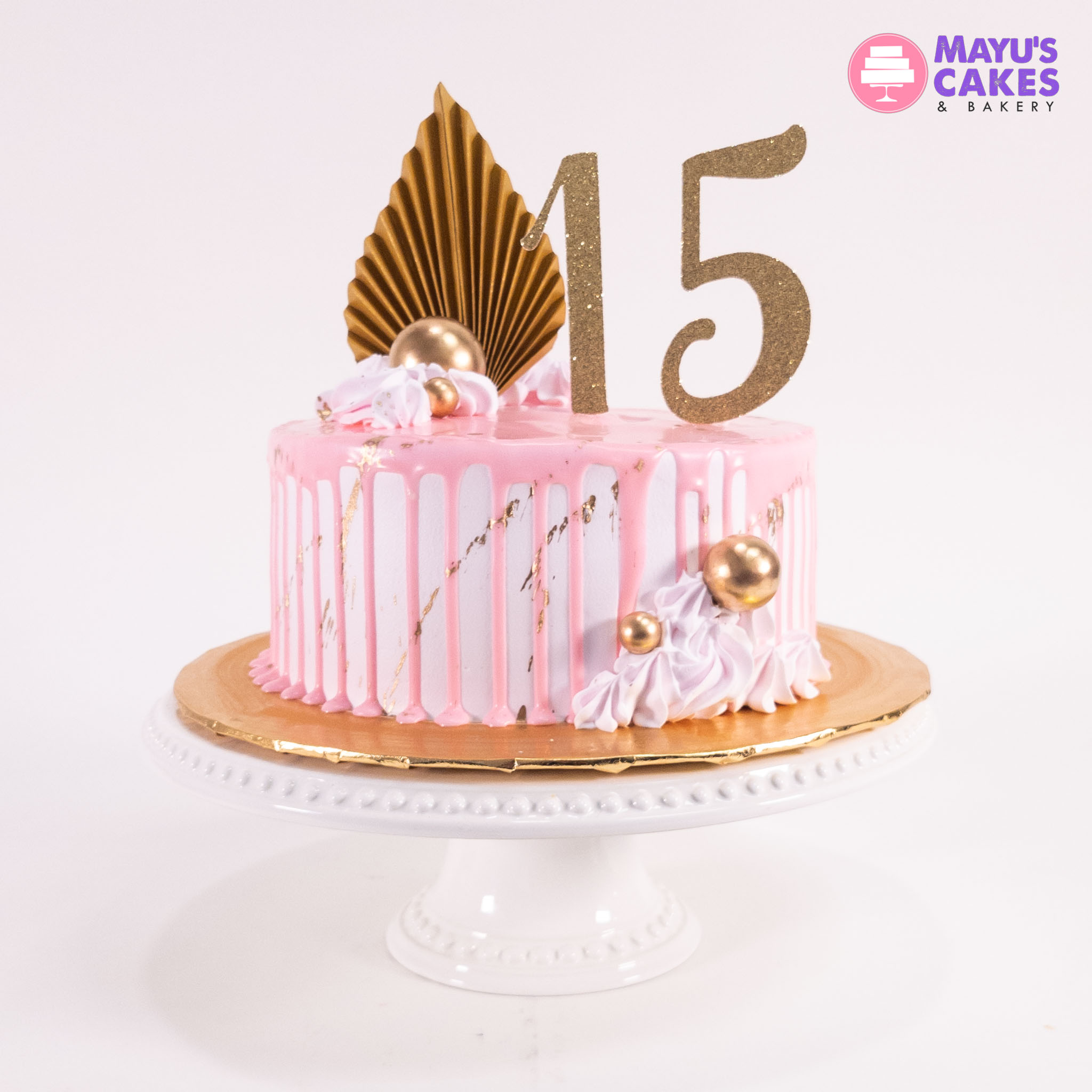 Pink and white cake with gold decorations and the number 15 on top.