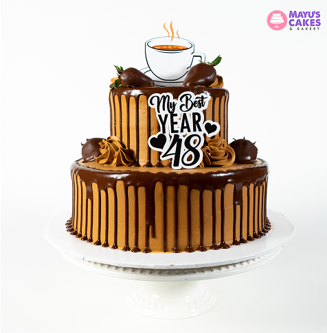 Two-tier chocolate cake with 'My Best Year 48' topper and chocolate-covered strawberries.