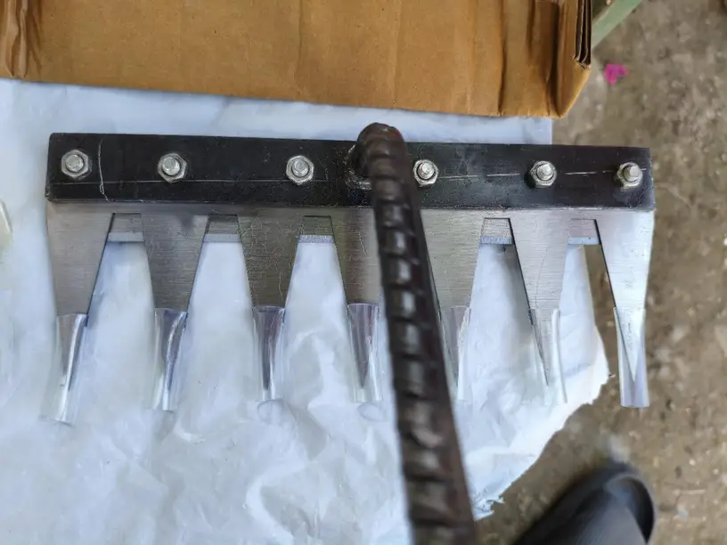Homemade garden tool with sharp metal spikes attached to a handle.