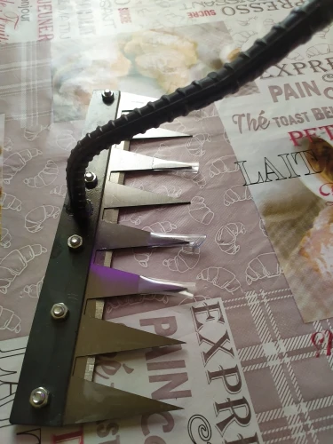 Metal rake heads with screws on a patterned tile floor.