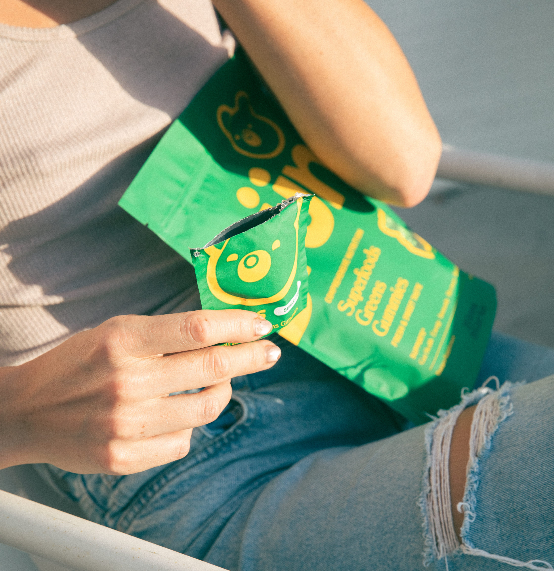 Person holding a green package with a bear logo, sitting on a chair.