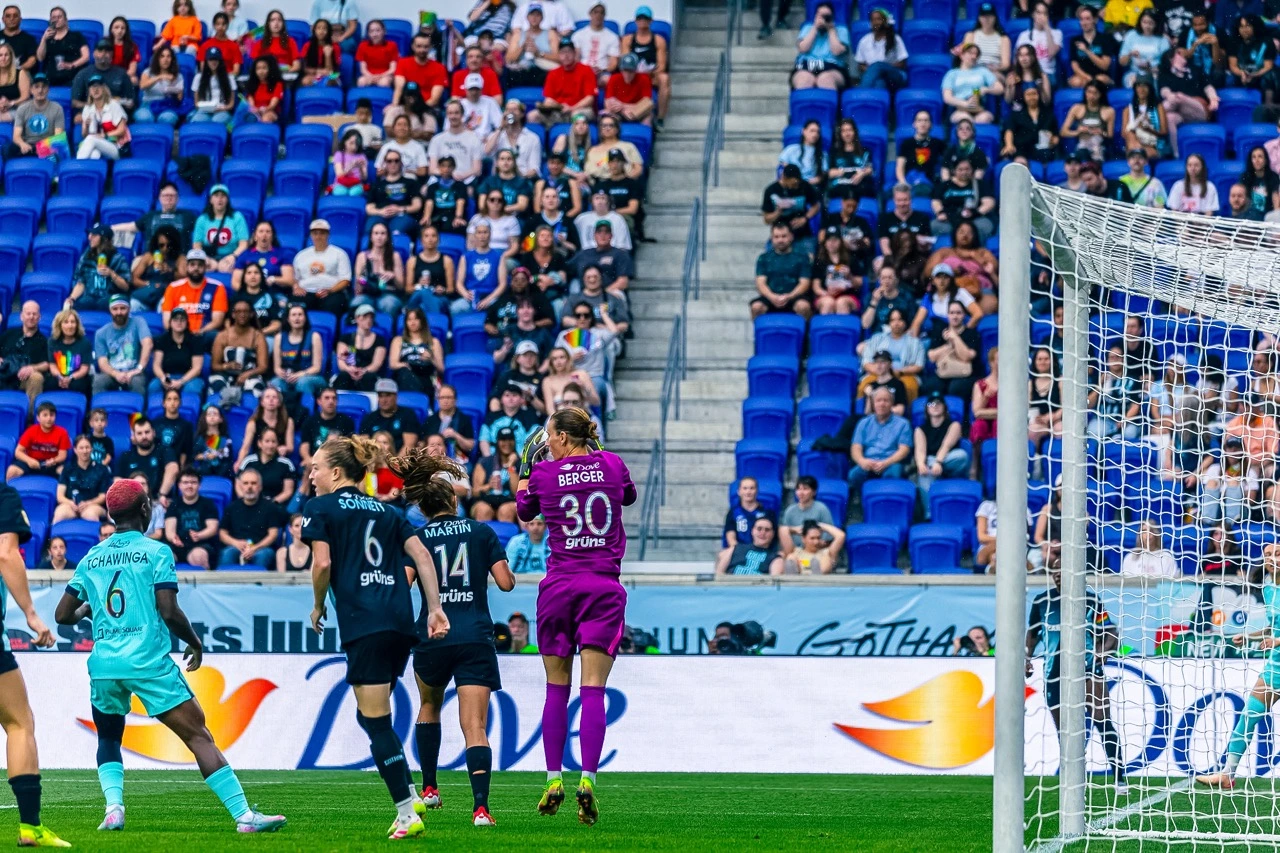 Soccer match with players near the goal and a crowd in the background.