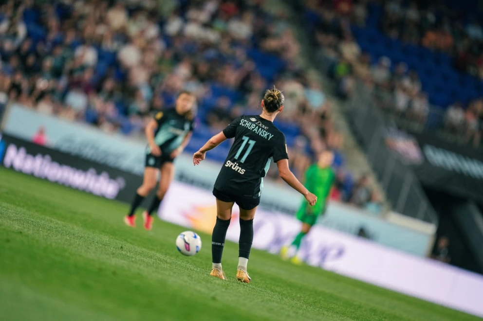 Soccer player on field with blurred crowd in background.