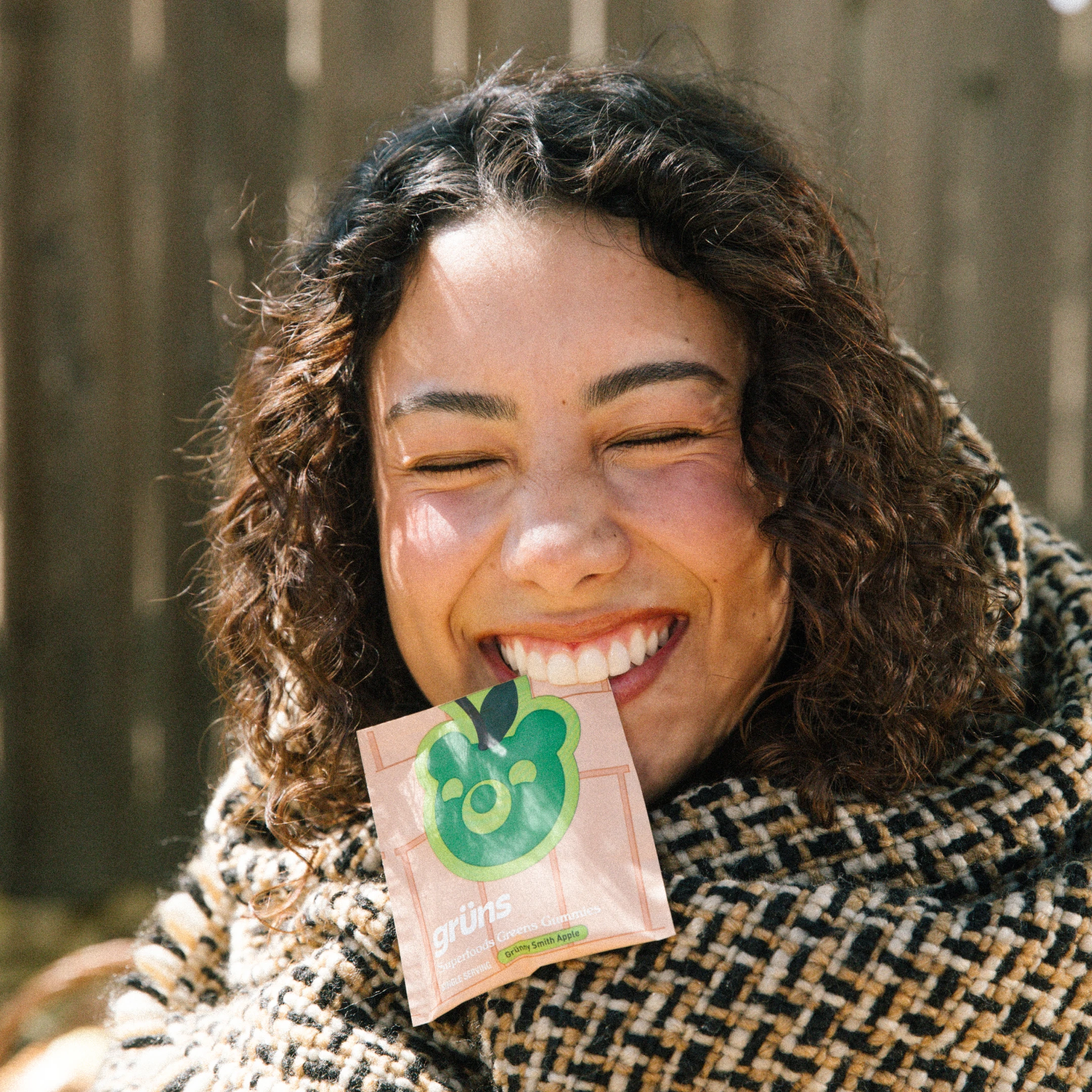 Smiling person holding a packet with a green apple design.