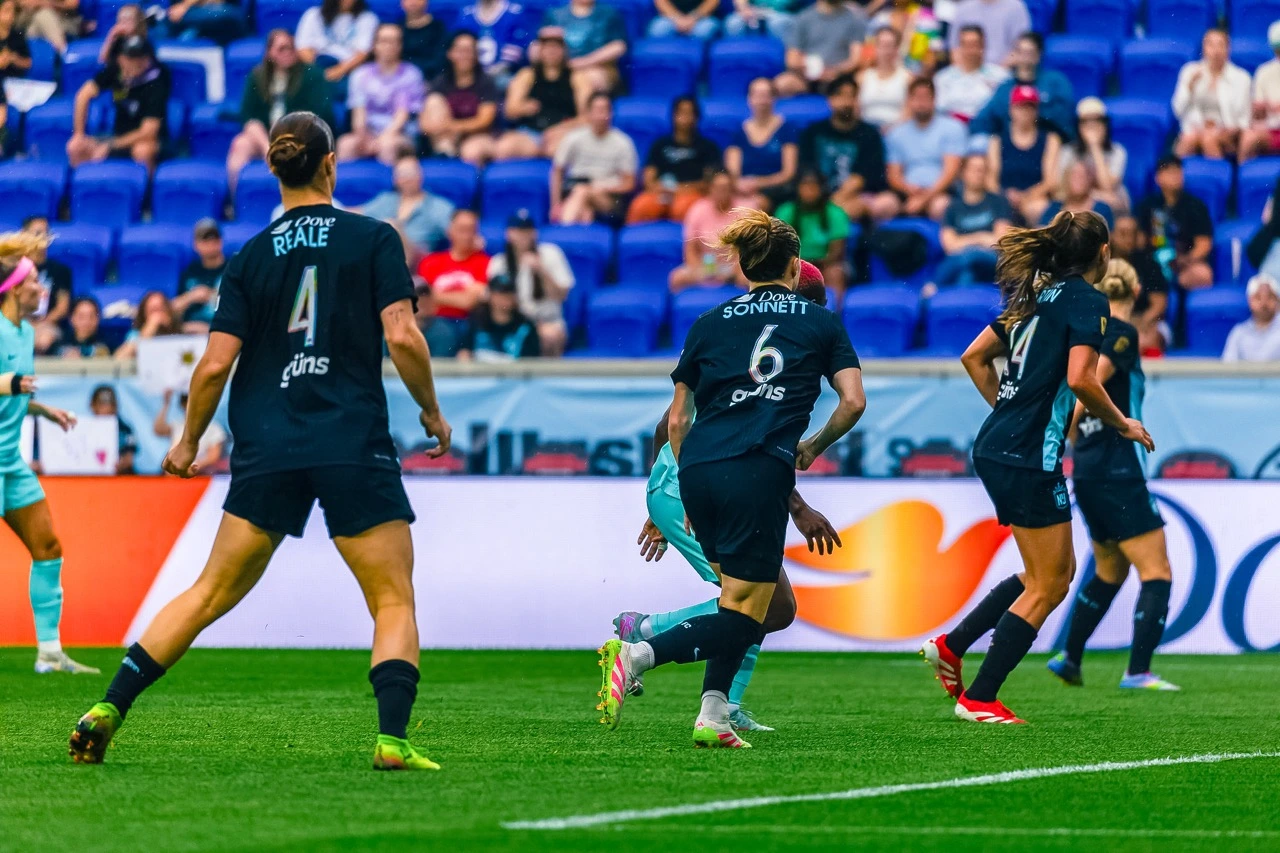 Soccer players in action on the field with spectators in the background.