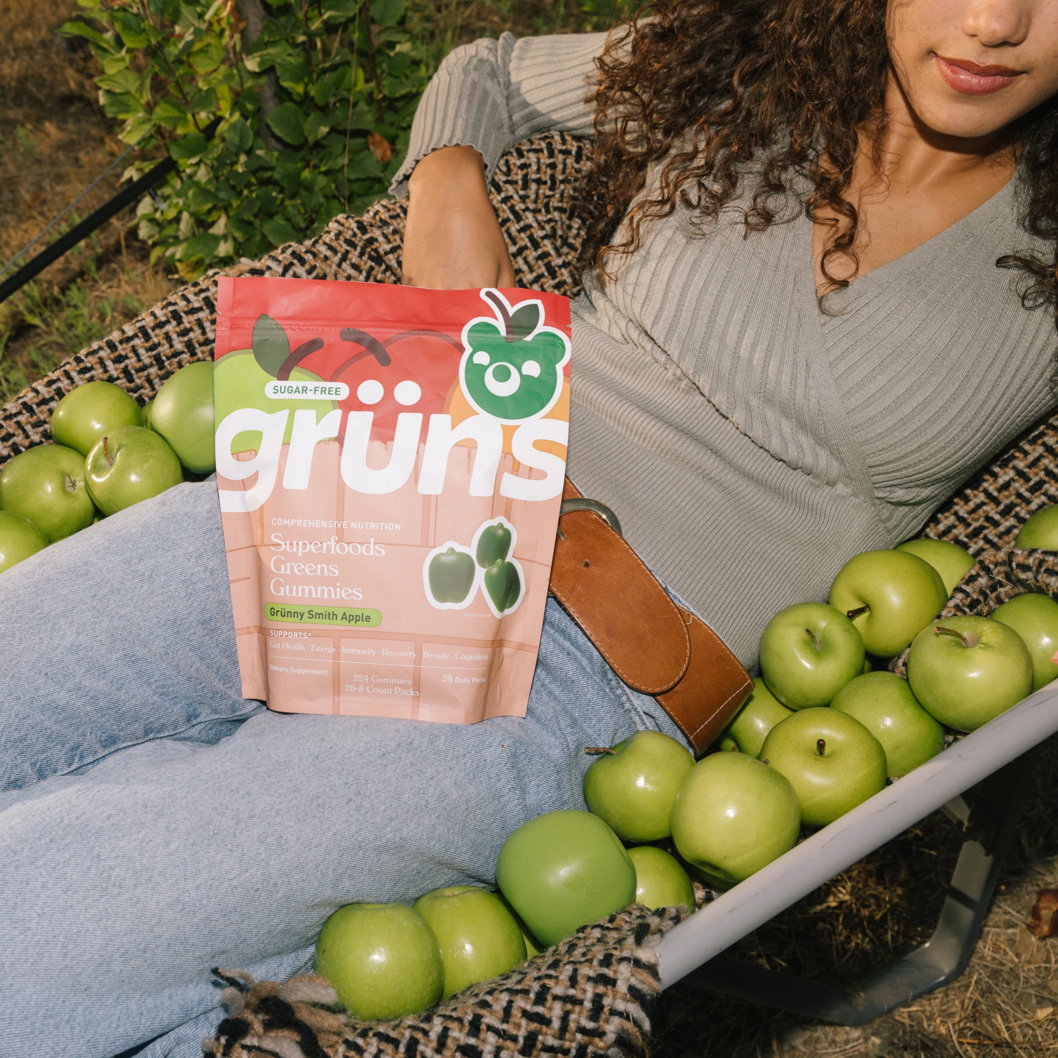 Person holding a bag of gummies surrounded by green apples.