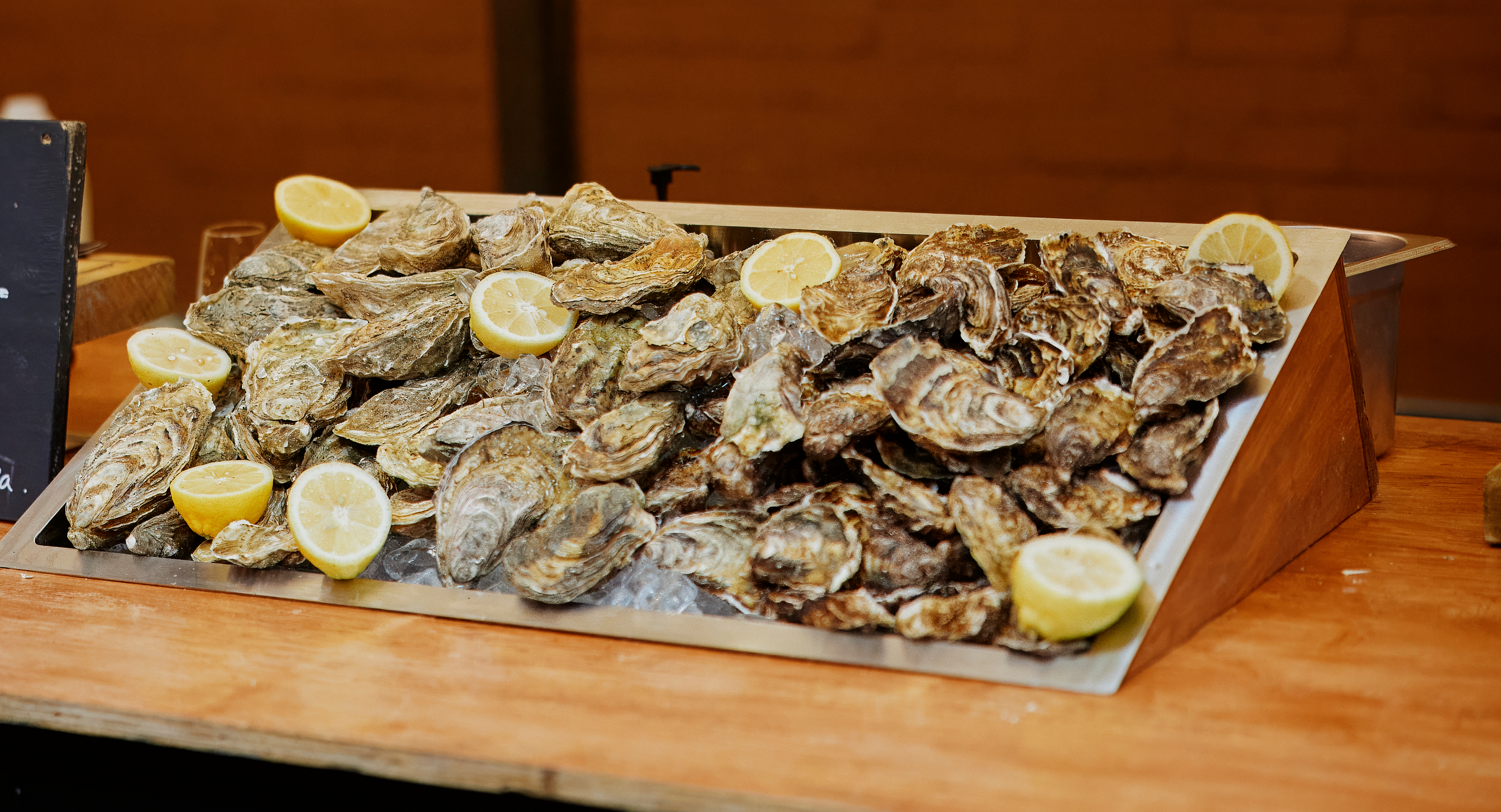 A tray of oysters with lemon slices on ice.