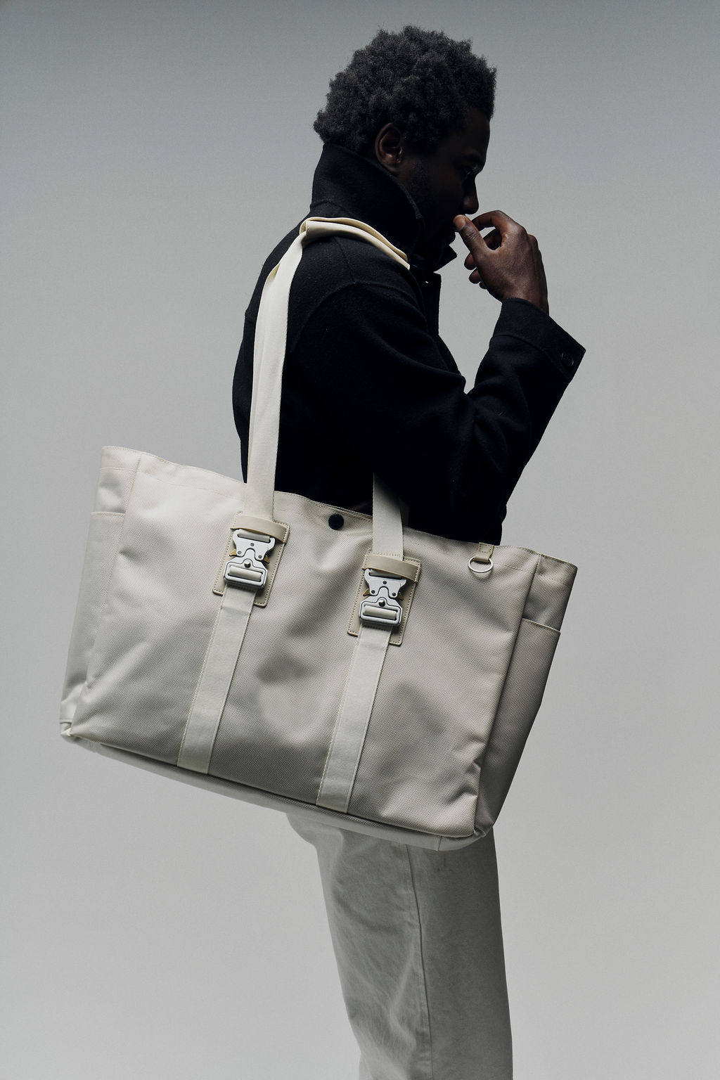 Person in black coat carrying a large beige bag.