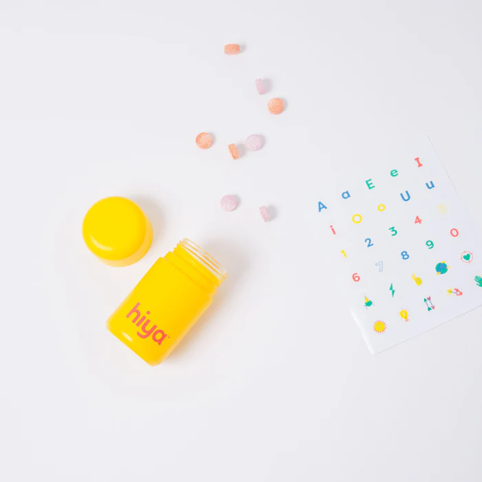 Yellow bottle with pills and a colorful alphabet sticker sheet.