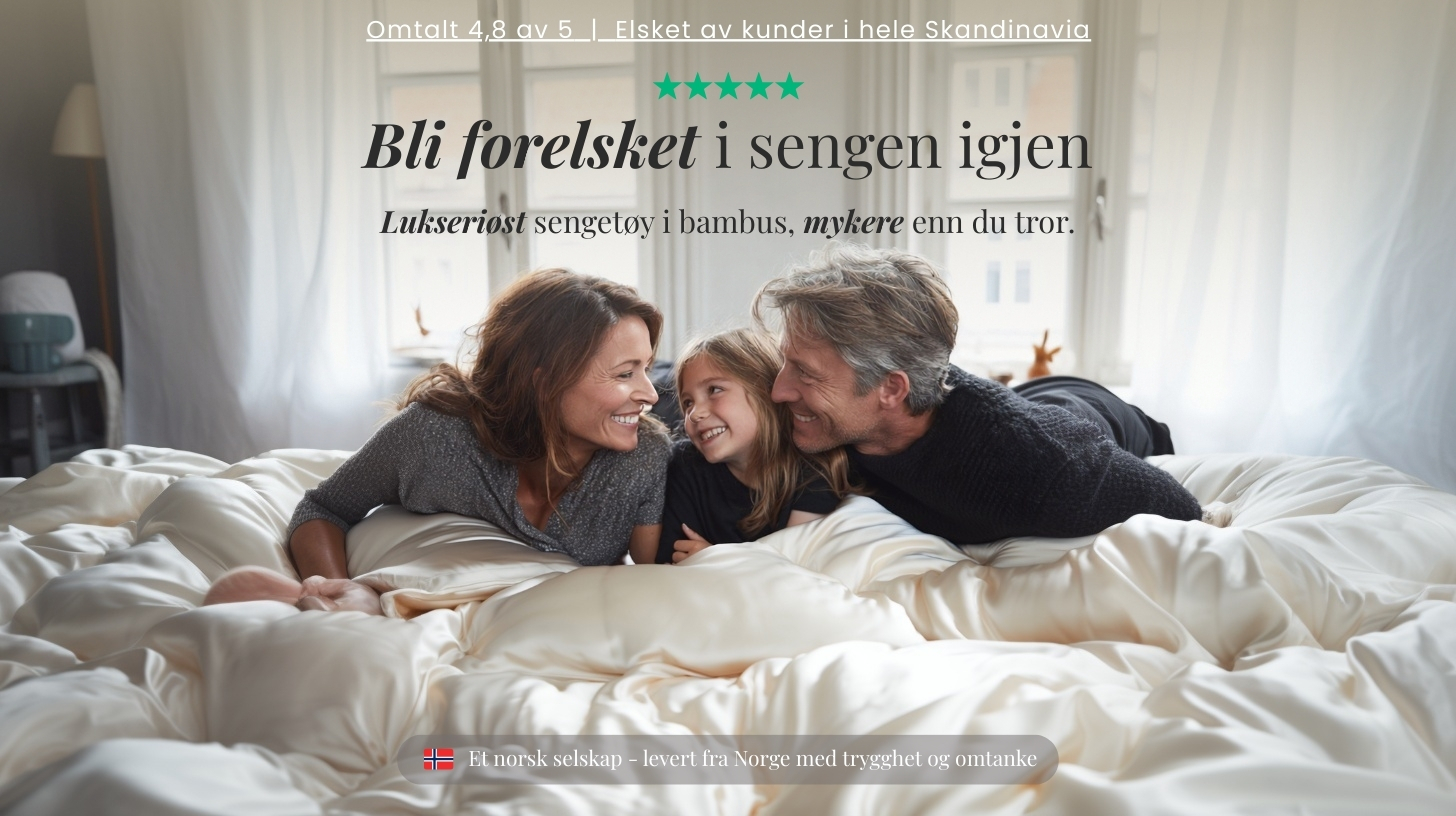 A smiling family with a young daughter lies together in bed on a cream-colored, silky duvet.