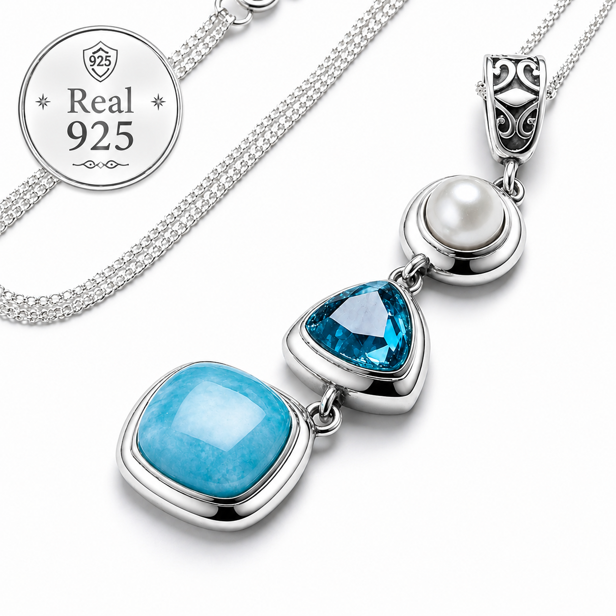 A close-up of a sterling silver necklace with a pendant featuring a pearl and two blue gemstones.