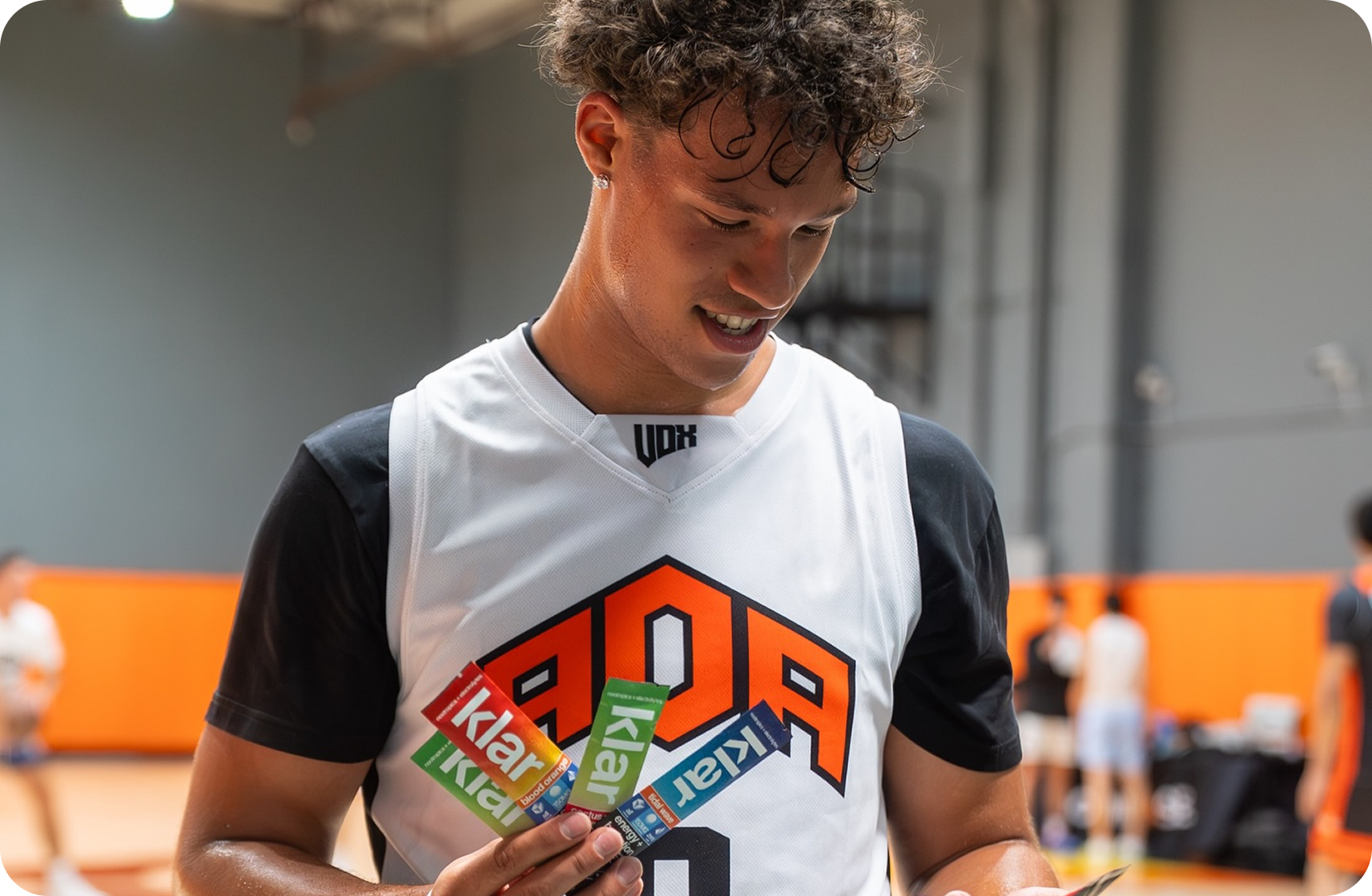 Person in a sports jersey holding colorful snack bars indoors.
