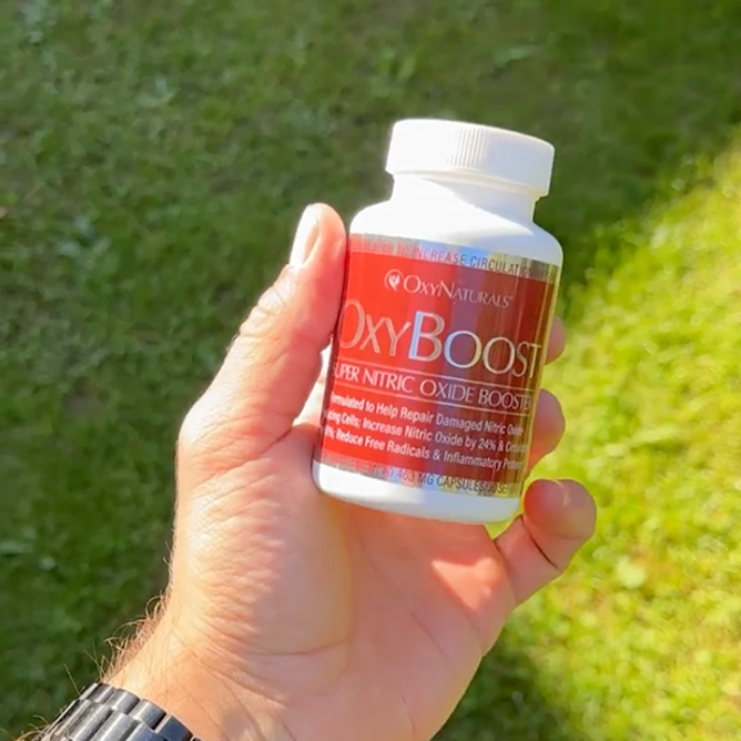 Hand holding a bottle labeled 'OxyBoost' against a grassy background.