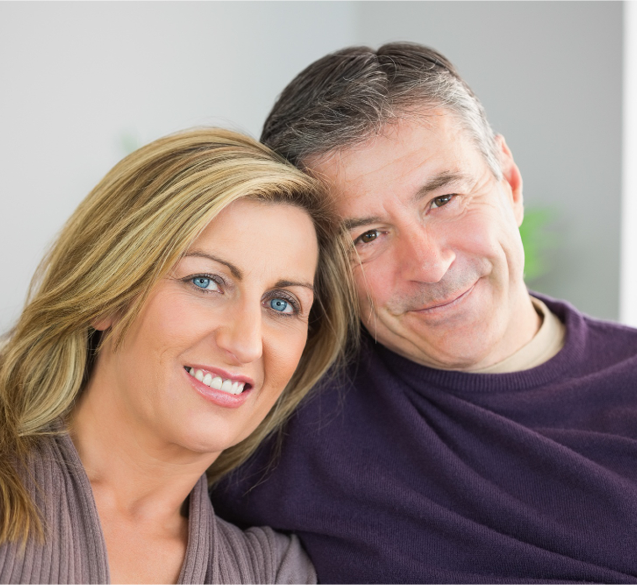 Smiling couple sitting closely together indoors.