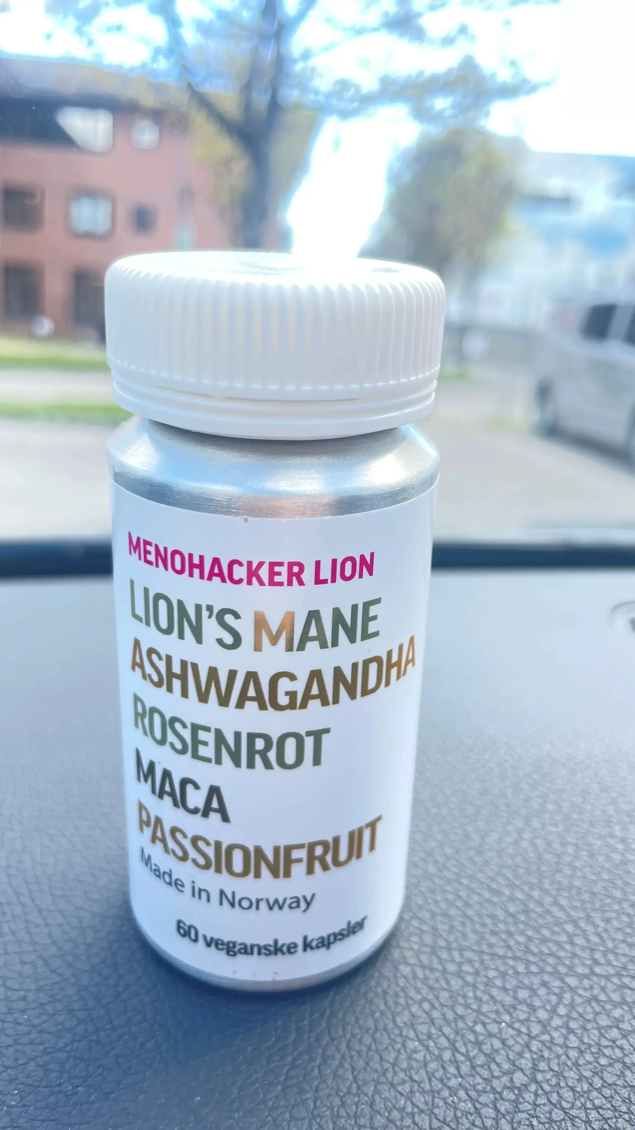 A close-up photo of a silver bottle of Menohacker Lion supplements with a white cap.