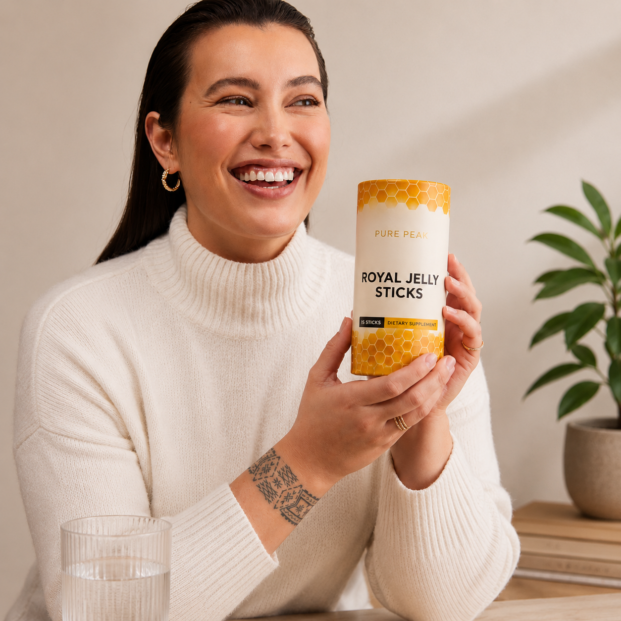 A smiling woman in a white sweater holds a container of Pure Peak Royal Jelly Sticks.
