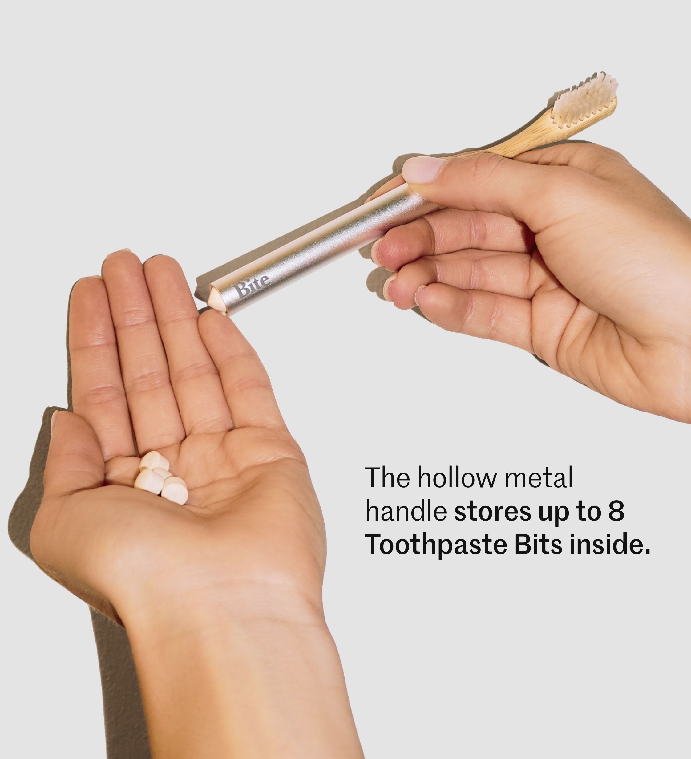 Hands holding a travel toothbrush with a hollow handle and toothpaste tablets that store inside.