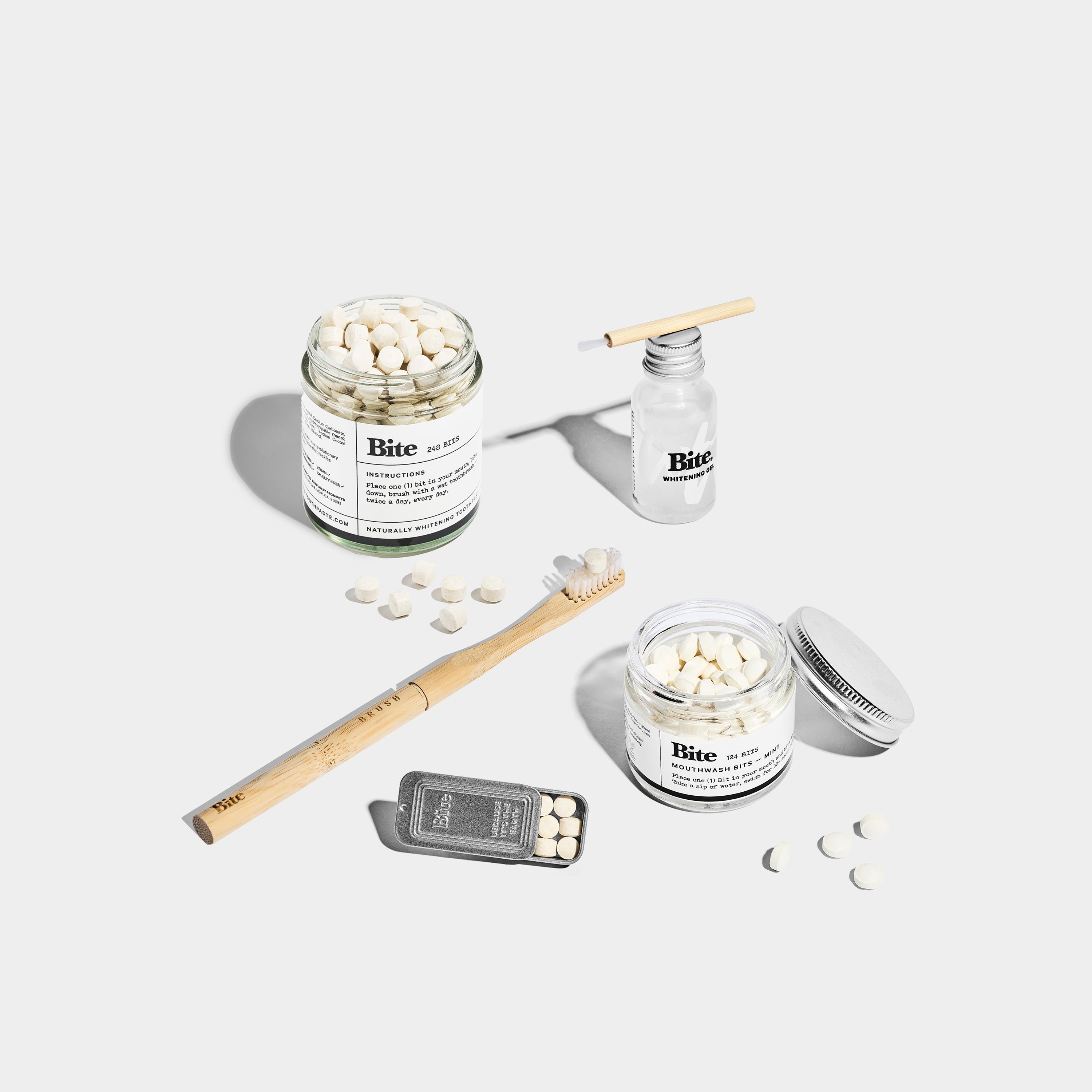 A glass jar and a metal container of Bite toothpaste bits sitting on a glass shelf.