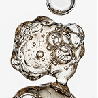 A close-up of a clear, amber-tinted gel with bubbles, suspended against a white background.
