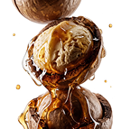 A stack of macadamia nuts, one cracked open with a scoop of ice cream and caramel sauce.