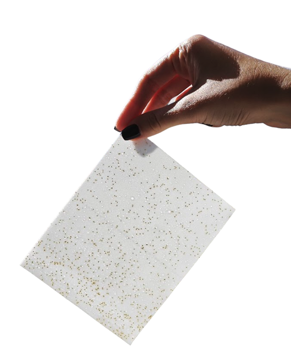 Hand holding glittery white sheet against black background.