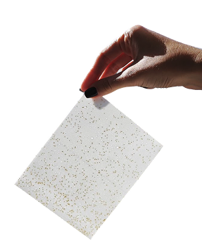 Hand holding glittery white sheet against black background.