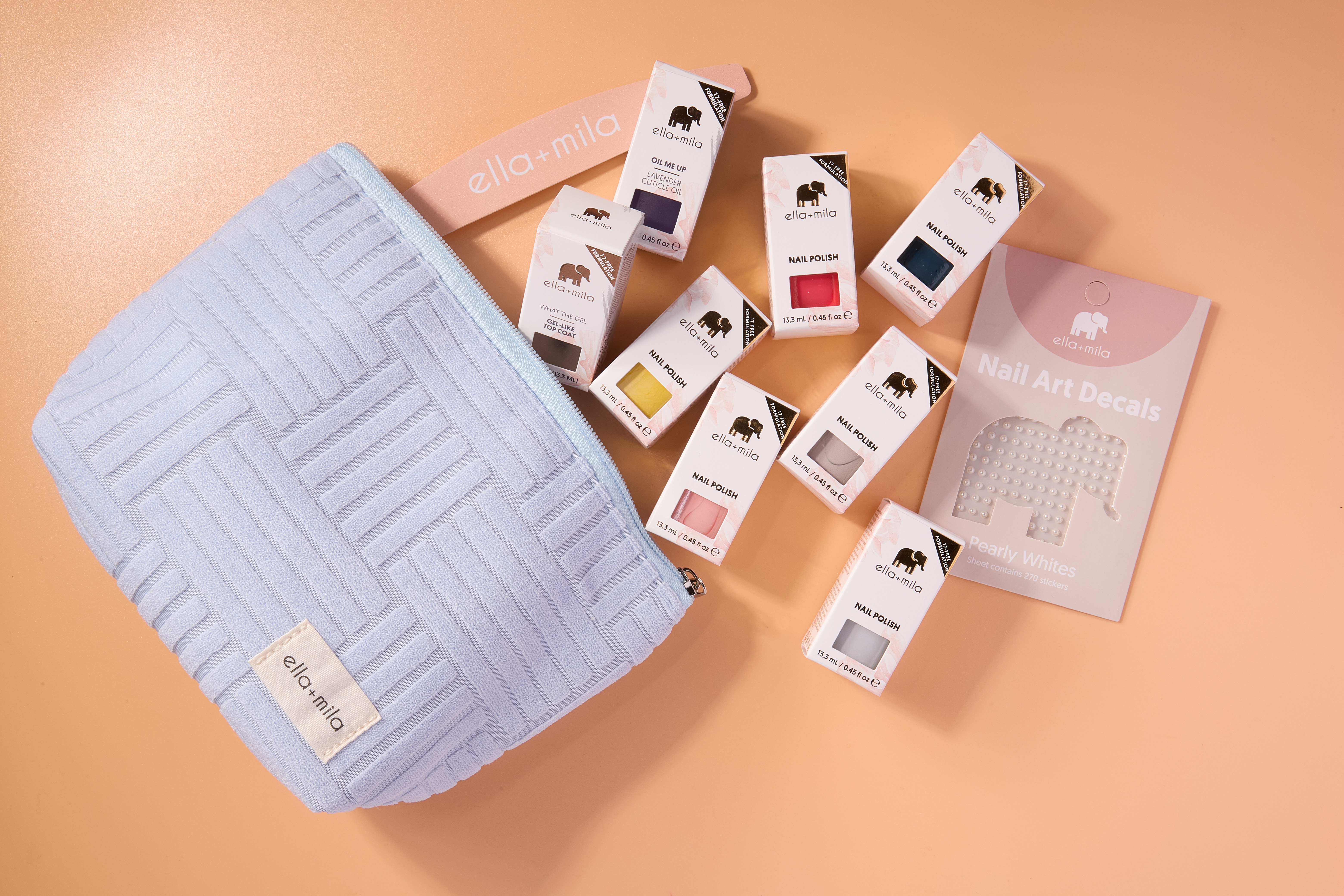 Nail polish bottles, nail art decals, and a blue pouch on a peach background.