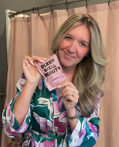 Person holding 'Sleep Well Beauty' package in front of a pink curtain.