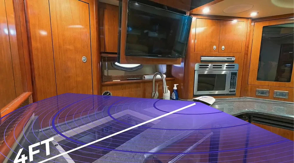 The kitchen galley of a boat with wood cabinets, with a purple graphic overlay showing a 4ft measurement.