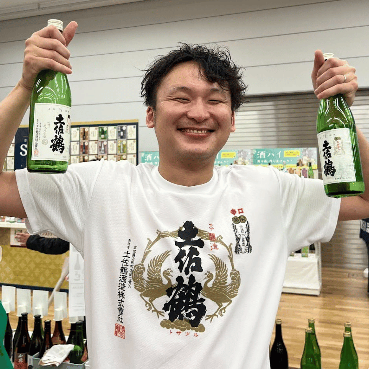 Kenta Nishikawa of Tosatsuru Brewing Company holding two bottles of Tosatsuru
