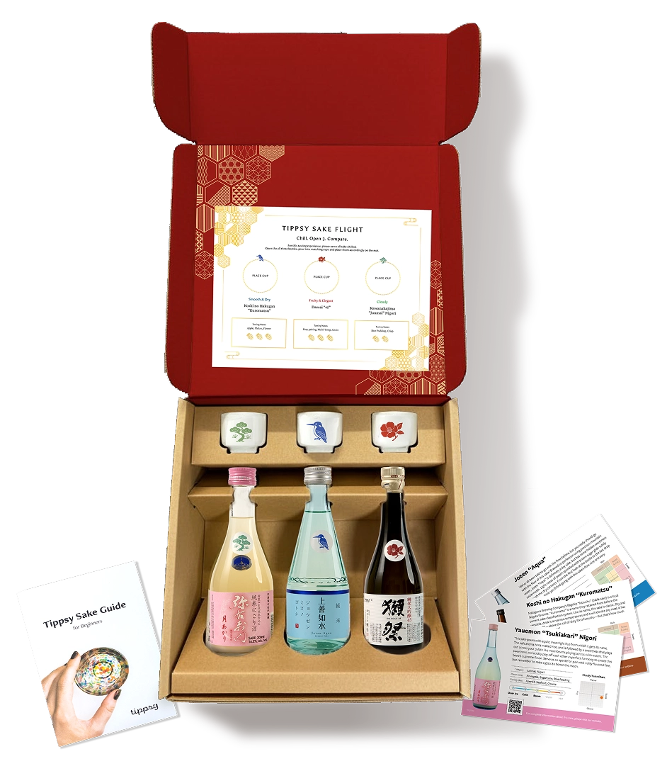 Open red box with sake bottles, cups, and informative cards.