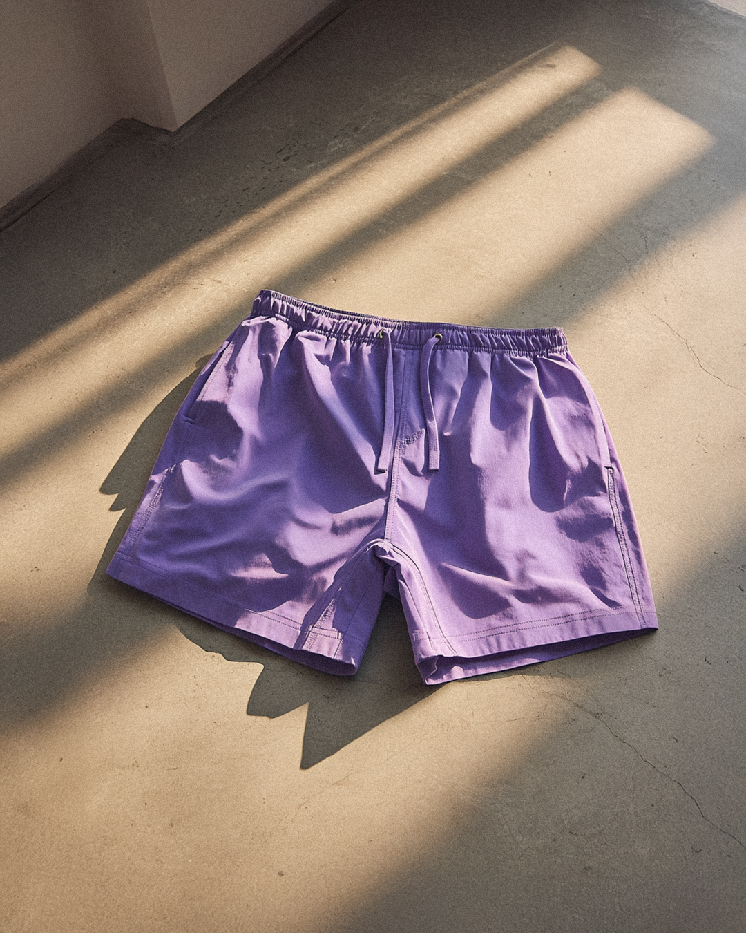 Purple shorts on a sunlit concrete floor.